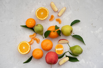 Many different fruits: tangerines, oranges, grapefruits, apples and pears on grey background. Fruits contain many vitamins. Fresh juices are good for healthy lifestyle. Close-up. Top view.