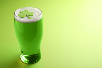 Glass of beer with clover leaf on green background, space for text. St Patrick's Day celebration