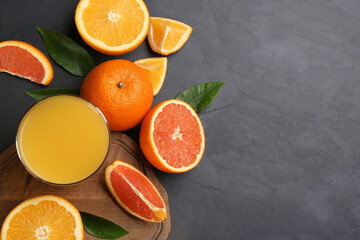 Delicious orange juice and fresh fruits on black table, flat lay. Space for text