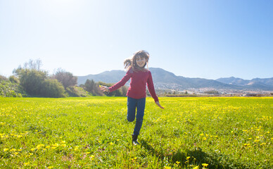 Fototapeta premium Concepto de una niña corriendo por un campo lleno de flores amarillas.