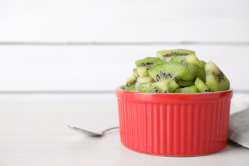 Bowl with kiwi slices on white table. Space for text