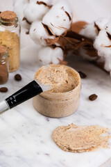 Natural body coffee scrub on marble background. Cosmetic face cream container with care cruelty-free product. Flat lay, top view