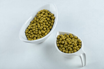 Two white bowls full with green marinated olives