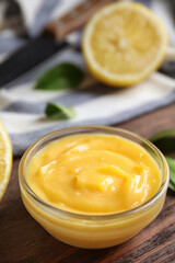 Delicious lemon curd in bowl on wooden table. Space for text