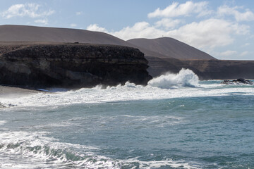 Fototapeta premium Ocean view on Ajuí beach. Beautiful view of the clear sea, waves, cliffs and beach in Playa de Ajuí - Canary Islands, Fuerteventura, Spain. 
