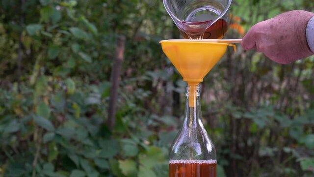 Pouring Natural Apple Cider Vinegar into sterile glass bottles (Acetum) - (4K)