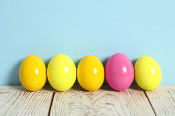 Easter eggs on white wooden table against light blue background, space for text