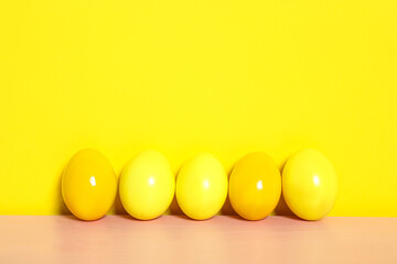 Easter eggs on pink wooden table against yellow background, space for text