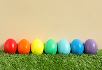 Bright Easter eggs on green grass against beige background