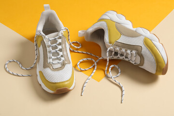 Pair of stylish shoes with laces on color background