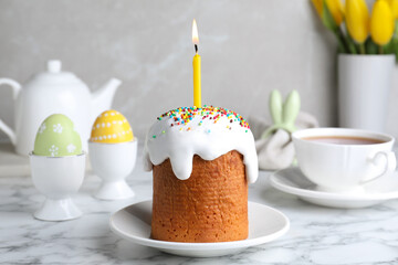Beautiful Easter cake with candle on white marble table