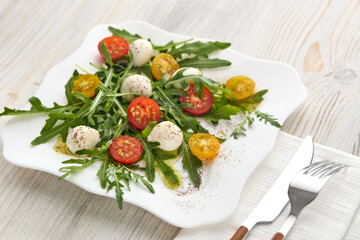 Dietary salad with mozzarella cheese, cherry tomatoes and arugula.