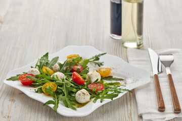 Dietary salad with mozzarella cheese, cherry tomatoes and arugula.