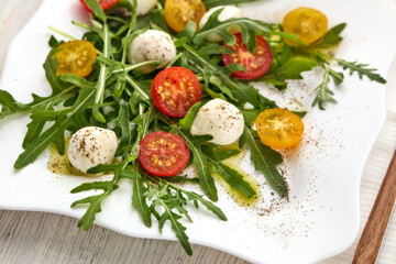 Dietary salad with mozzarella cheese, cherry tomatoes and arugula.