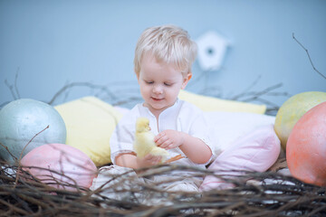Fototapeta na wymiar little boy sits in a nest with eggs and holds a duckling. Easter