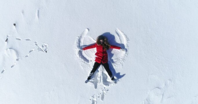 girl lies in the snow and makes an angel.