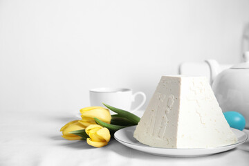 Traditional cottage cheese Easter paskha and yellow tulips on white fabric, space for text