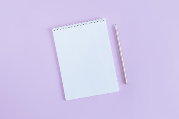 Notebook with blank page and pencil on a violet pastel background.