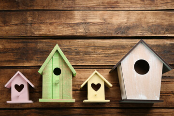Collection of handmade bird houses on wooden background, flat lay. Space for text