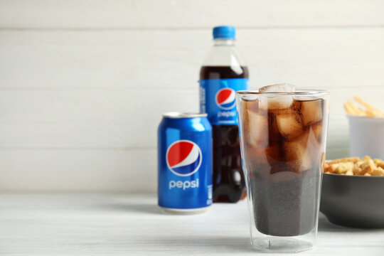 MYKOLAIV, UKRAINE - FEBRUARY 15, 2021: Glass of Pepsi and snack on white wooden table, space for text