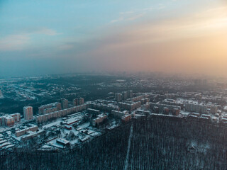 Aerial view Kharkiv city Pavlove Pole district. Winter dark forest, multistorey houses and snowy sunset sky