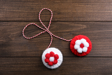 Traditional martisor with flowers on wooden background, top view. Beginning of spring celebration