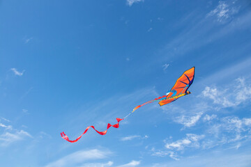 Dragon kite flying against a wild and cloudy blue sky.