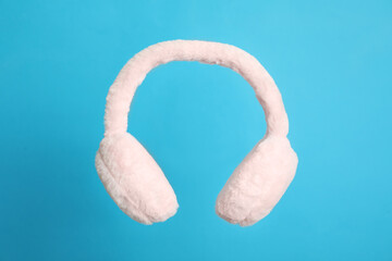 Stylish winter earmuffs on light blue background