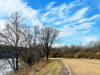 Fototapeta na wymiar Curving road along a river in winter with dramatic clouds in a blue sky