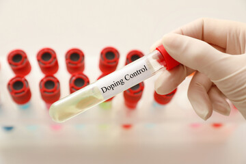 Fototapeta premium Doctor holding test tube with sample over table, closeup. Doping control
