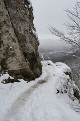 Fototapeta na wymiar Mountain trail that gets lost behind the rock with nice snowy views