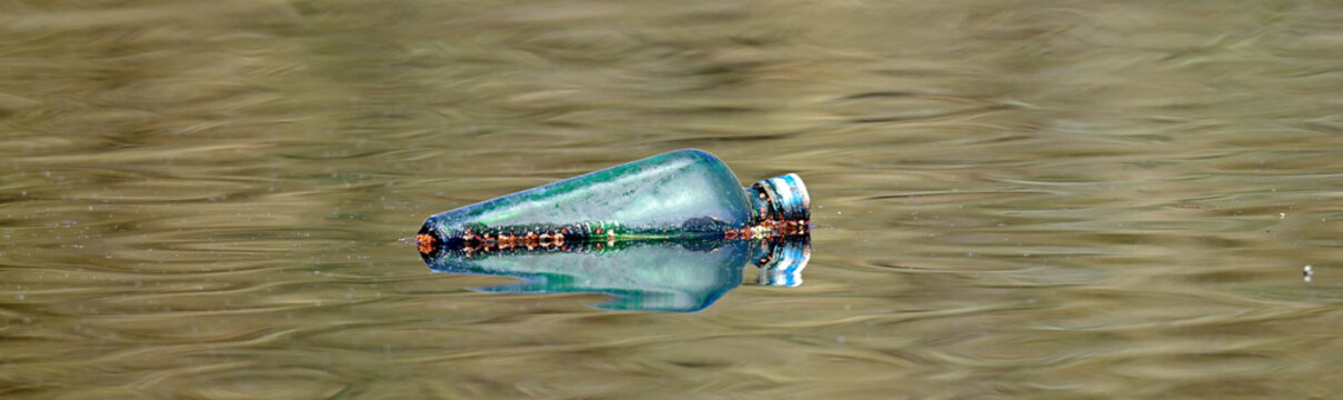 alte, weggeworfene Glasflasche schwimmt in einem See // old, discarded glass bottle floats in a lake