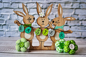 Three wooden Easter bunnies with decoration and the text Easter written on eggs.