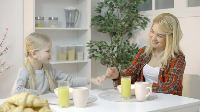 Little girl making pinky swear with smiling mother, promise to parent, trust