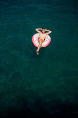 Young woman in a swimsuit swims on an inflatable ring in the sea. Summer vacation concept.