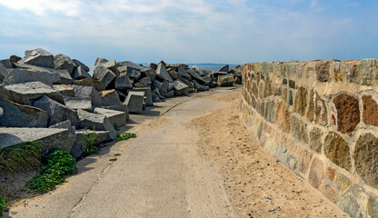 way on a mole between  granite blocks as wave breakers and an upright stone wall at the harbour of Sassnitz, Germany