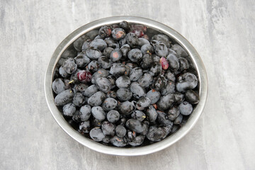 Close up view of a stainless steel bowl with just freshly harvested  raw blue olives