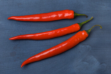 Three red chili peppers on a blue background