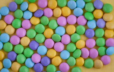 Fototapeta na wymiar Pastel colored candy on a yellow background, easter background, soft focus