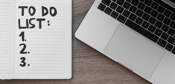 TO DO List, laptop on desk. Wooden table, working from home concept of organising daily tasks, black marker letters and bullet points one to three. Copy space for text, overlay top view.