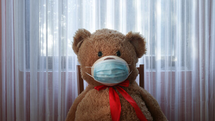 Teddy Bear wearing medical mask to emphasize the social aspect of self isolation and loneliness that happens when one is alone, lonely teddy bear. Panorama coronavirus covid-19 global pandemic Banner