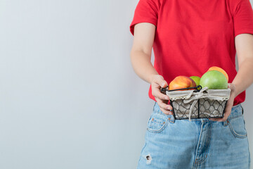 A person holding a fruit basket in the hand