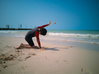 Boy throwing sand on the beach