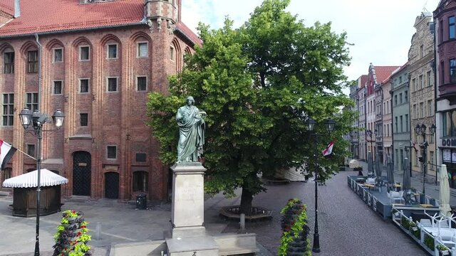 Rynek Staromiejski In Toruń, Poland, with the Town Hall and the statue of Nicolaus Copernicus in the foreground. In the distance, a panorama of Toruń with tenement houses and the Vistula River.