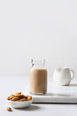 Almond milk in glass bottle and nuts on white background. Close up. Lack of cholesterol.