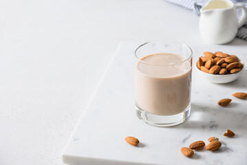 Almond milk in glass bottle and nuts on white background. Close up. View from above. Lack of cholesterol.