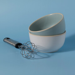 bowls and whisk on blue background. Kitchenware.
