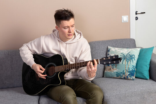Young man plays guitar at home. Musical hobby. Leisure during quarantine.