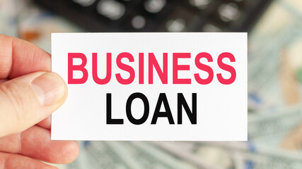 A man holds a piece of paper with the text: BUSINESS LOAN. Business and finance concept.