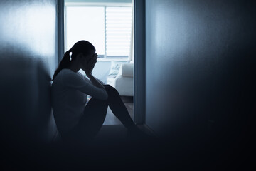 silhouette of a person feeling sad and tired sitting at home in the dark. 